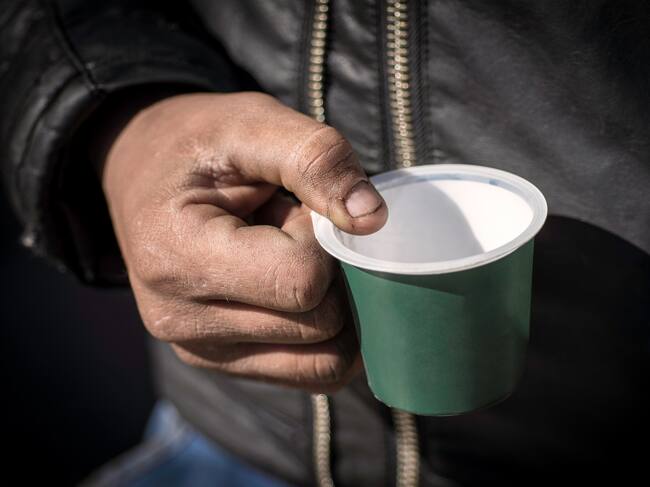 Dirty Beggar Hand Holding Plastic Cup. Poor Man Begging for Money on the Street Close Up.