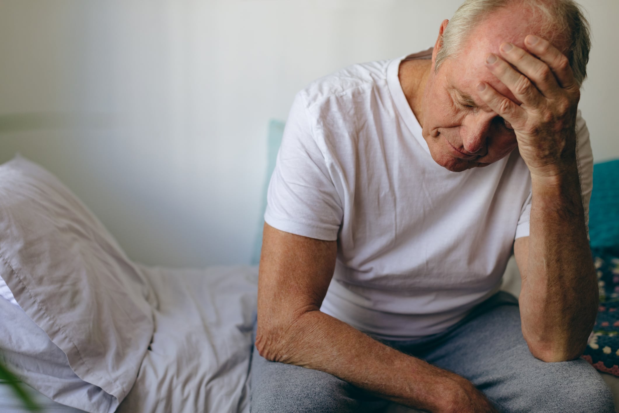 Imagen de un adulto mayor sentado en una cama, sosteniendo su cabeza con la mano en la frente (Crédito: Getty Images)