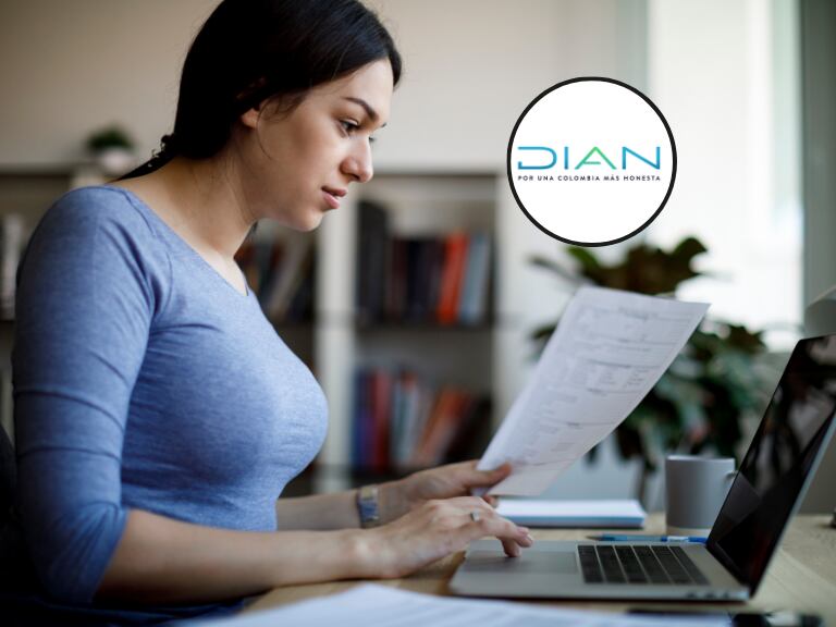 Mujer revisando un documento en el computados y de fondo el logo de la DIAN (Fotos vía Getty Images y página de Facebook oficial de la DIAN)