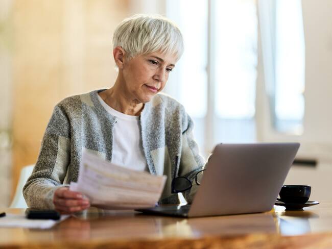 Mujer mayor revisando su cuenta en Internet a través del computador (Getty Images)