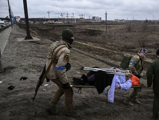 Soldados ayudan a una mujer herida en Irpin. Foto: Getty