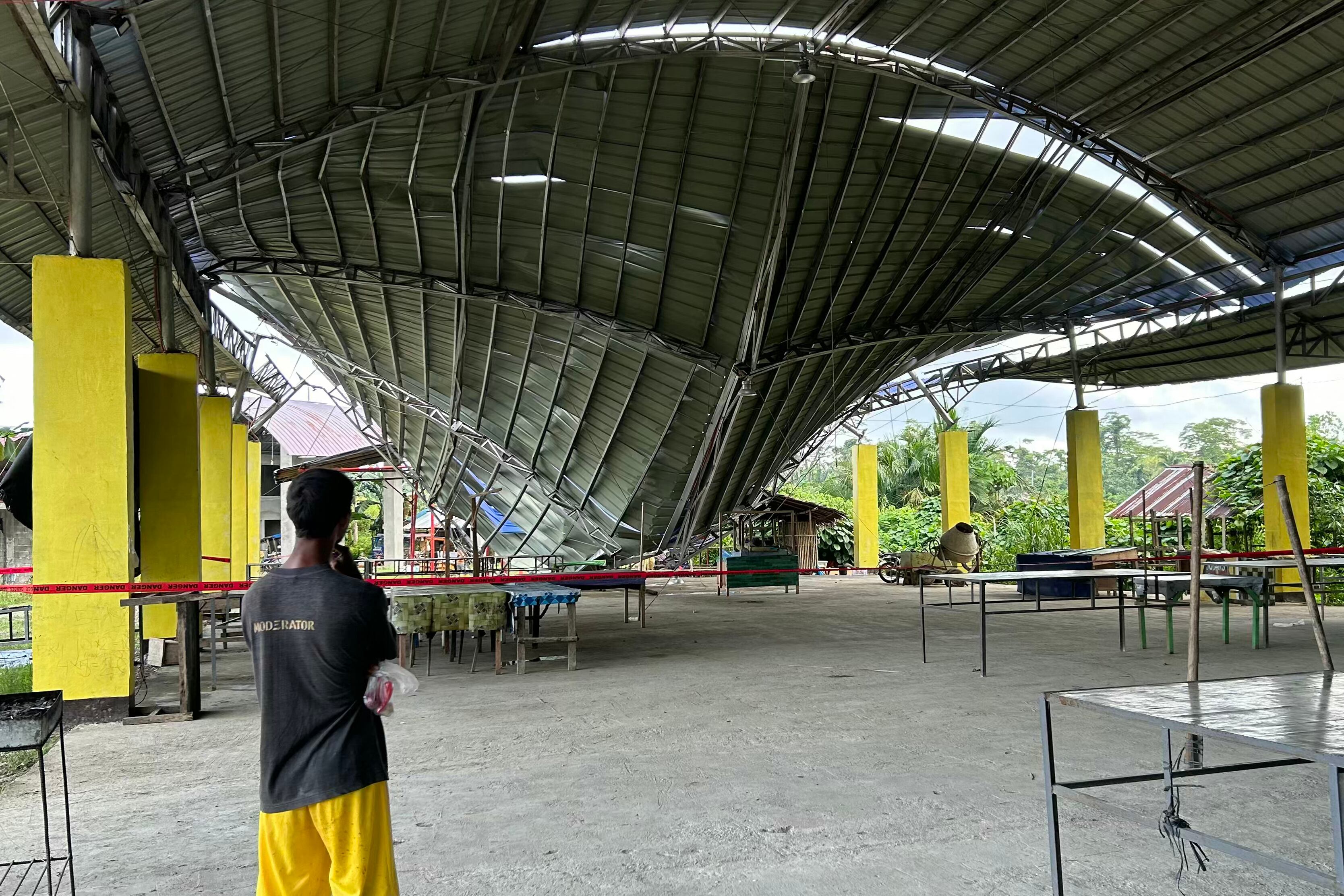 A person looks at the collapsed roof of a building following a 7.6 magnitude earthquake in Tagbina, Surigao del Sur province on December 3, 2023. At least two people were killed and several were injured after a magnitude 7.6 earthquake shook the southern Philippines late on December 2, triggering tsunami warnings that were later lifted. (Photo by AFP) (Photo by STR/AFP via Getty Images)