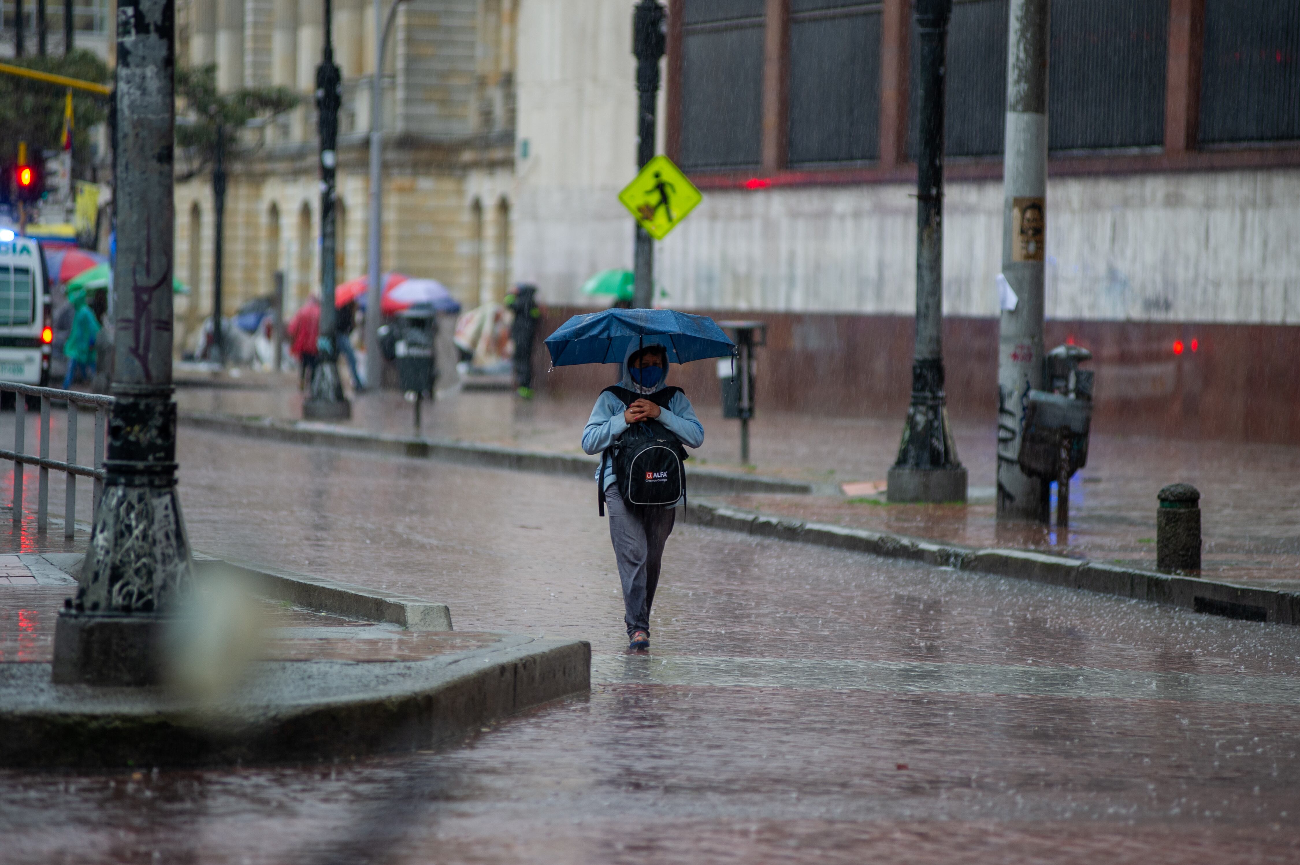 Mujer caminando bajo la lluvia en Bogotá (Foto vía GettyImages)