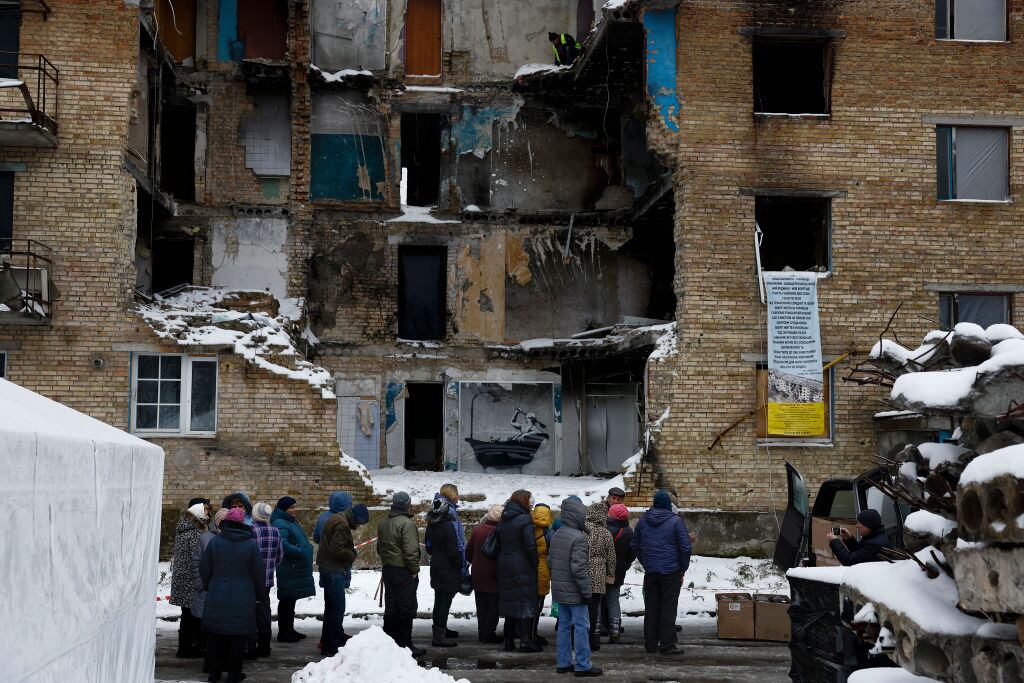 HORENKA, UKRAINE - NOVEMBER 22: Members of public queue for food beside a picture by graffiti artist Banksy on a the wall of a destroyed building on November 22, 2022 in Horenka, Ukraine. The elusive British artist posted a video to Instagram last week that suggested he's behind the spray-painted artworks that have appeared across the Ukrainian capital this month. (Photo by Jeff J Mitchell/Getty Images)