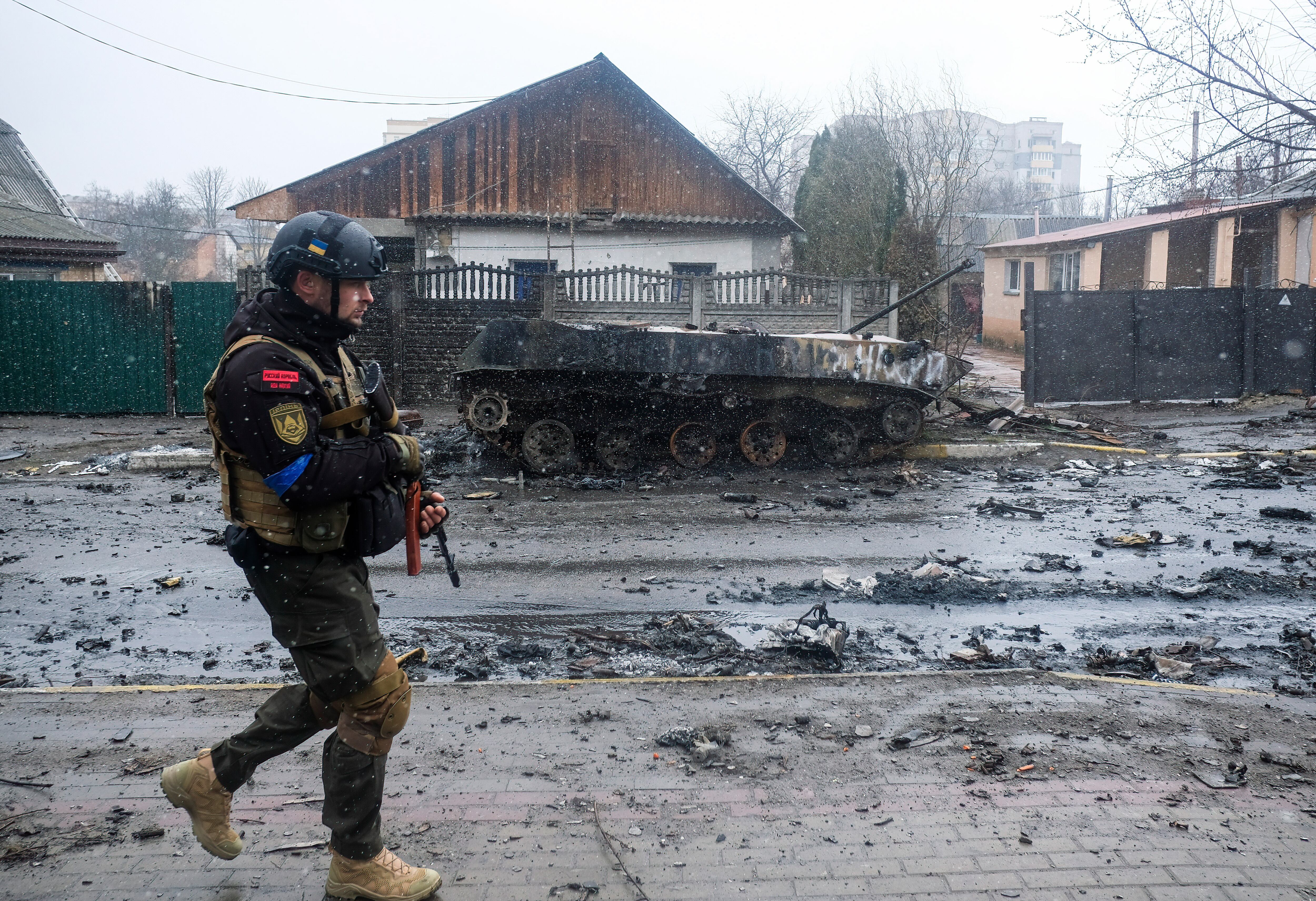BUCHA, UKRAINE - 2022/04/03: Ukrainian soldier inspects the wreckage of a destroyed Russian armored column on the road in Bucha, a suburb north of Kyiv. As Russian troops withdraw from areas north of Ukraine's capital city of Kyiv, Ukrainian forces and the media found evidence of significant numbers of civilian casualties. The Ukrainian authorities are calling the killing of civilians in Bucha and other areas a war crime. (Photo by Matthew Hatcher/SOPA Images/LightRocket via Getty Images)