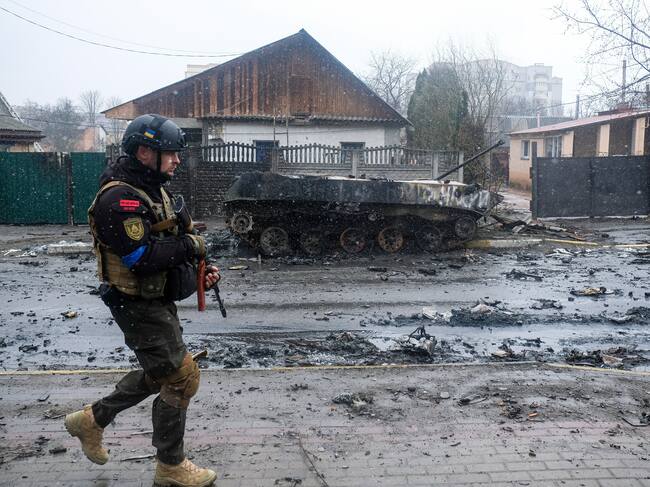 BUCHA, UKRAINE - 2022/04/03: Ukrainian soldier inspects the wreckage of a destroyed Russian armored column on the road in Bucha, a suburb north of Kyiv. As Russian troops withdraw from areas north of Ukraine's capital city of Kyiv, Ukrainian forces and the media found evidence of significant numbers of civilian casualties. The Ukrainian authorities are calling the killing of civilians in Bucha and other areas a war crime. (Photo by Matthew Hatcher/SOPA Images/LightRocket via Getty Images)