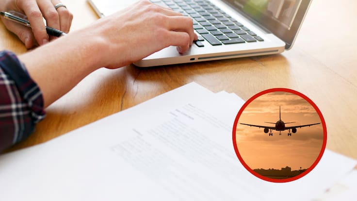 Hombre buscando información en un computador junto a la imagen de un avión (Foto vía Getty Images)