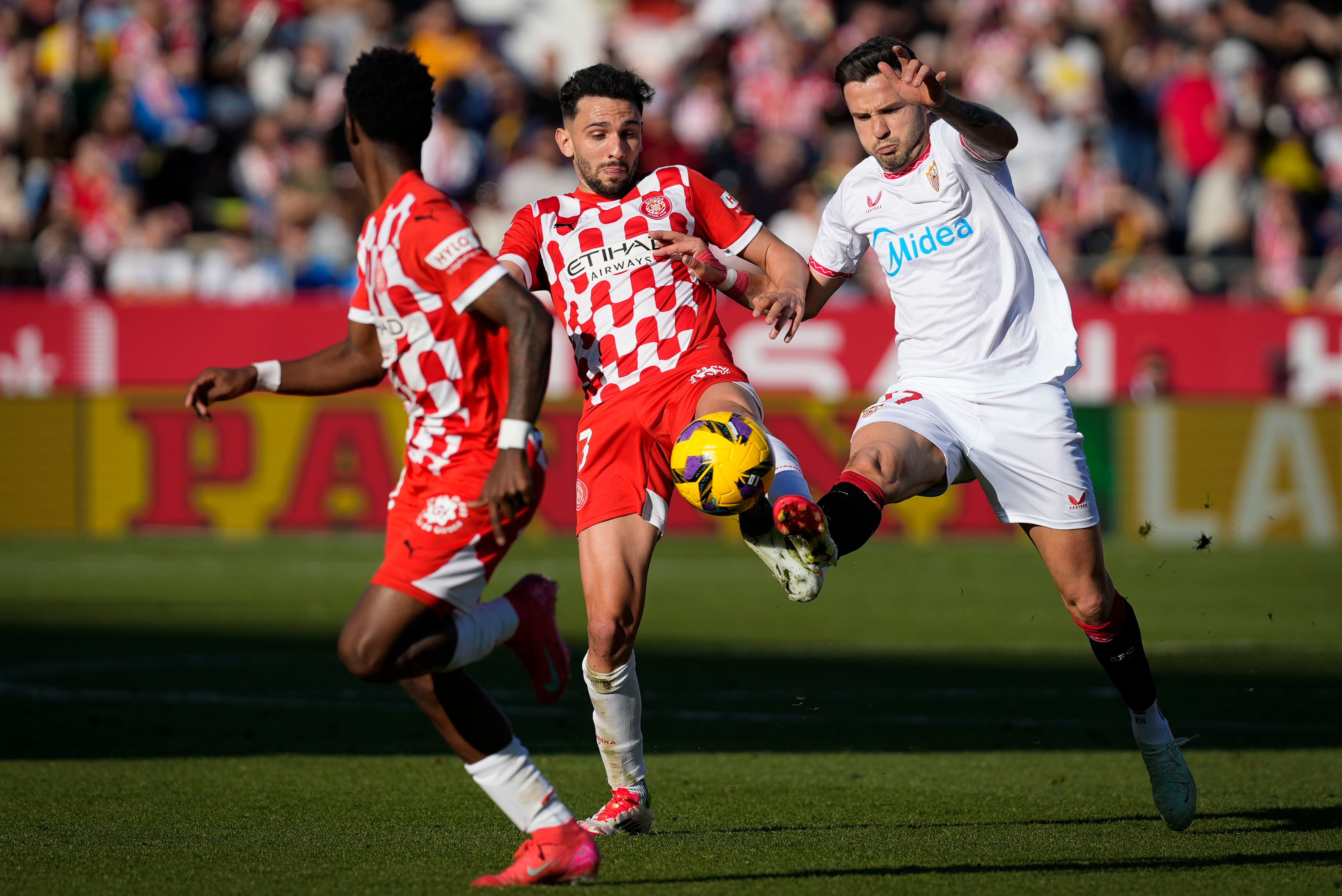 GIRONA, 18/01/2025.- El centrocampista del Girona Iván Martín (c) disputa un balón ante el centrocampista del Sevilla FC Saúl Ñíguez (d) durante el partido de LaLiga EA Sports en el Estadio de Montilivi de Girona este sábado. EFE/ David Borrat