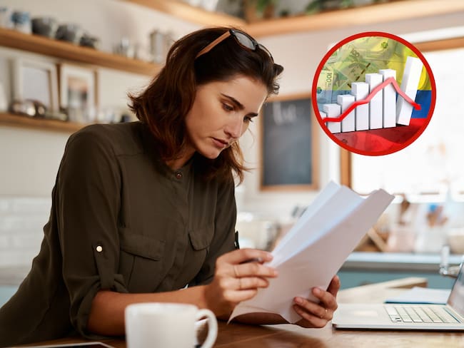 Mujer haciendo cuentas junto a una gráfica de economía (Fotos vía Getty Images)