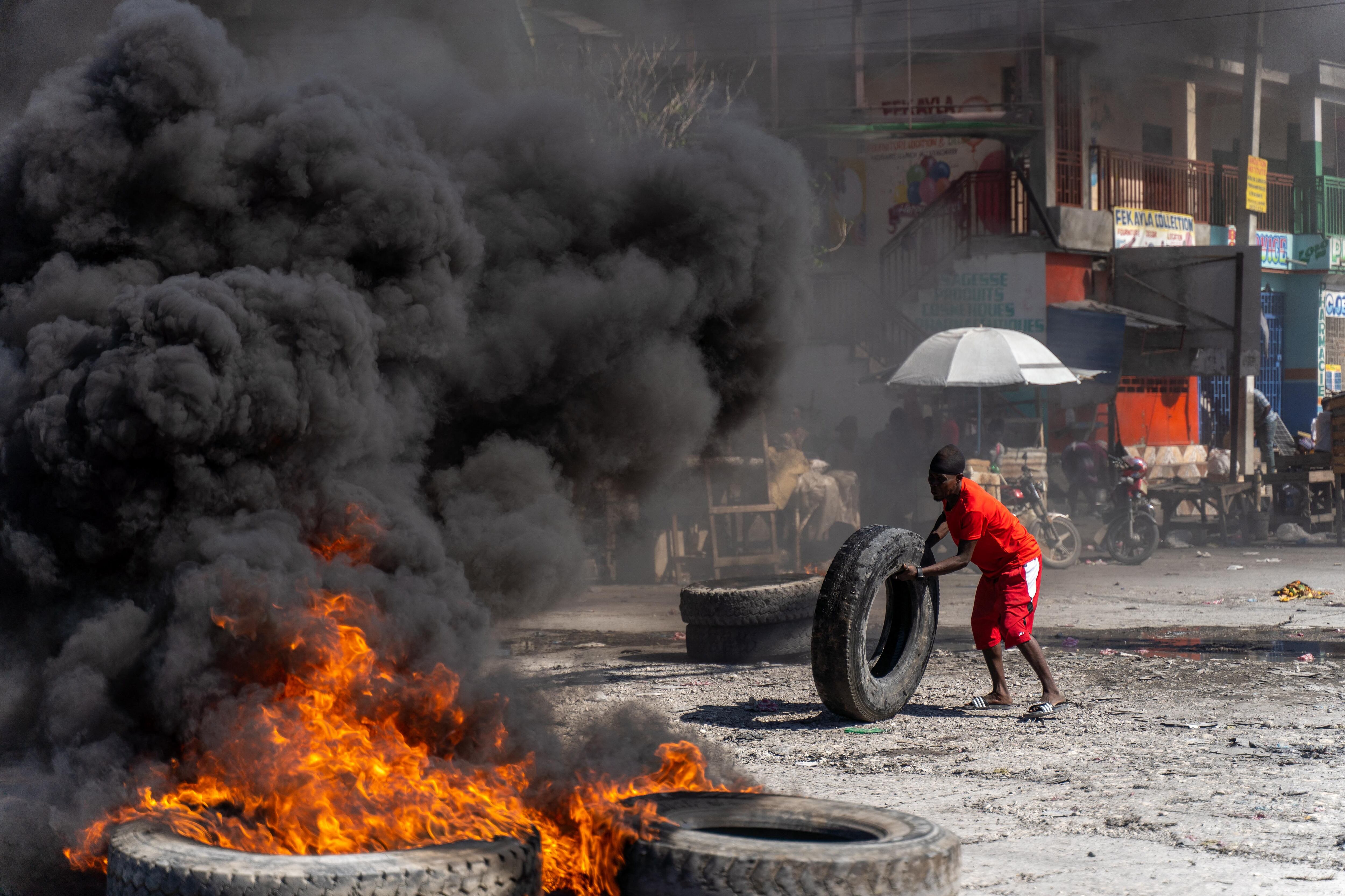 TOPSHOT - A protestor adds a tire to a burning barricade during a police demonstration to protest the recent killings of six police officers by armed gangs, in Port-au-Prince, Haiti, January 26, 2023. - The attacks, which left six officers dead, occurred on January 25 in the town of Liancourt, when officers had to repel four attacks by the gunmen as they tried to take over the station, according to local news. (Photo by Richard Pierrin / AFP) (Photo by RICHARD PIERRIN/AFP via Getty Images)