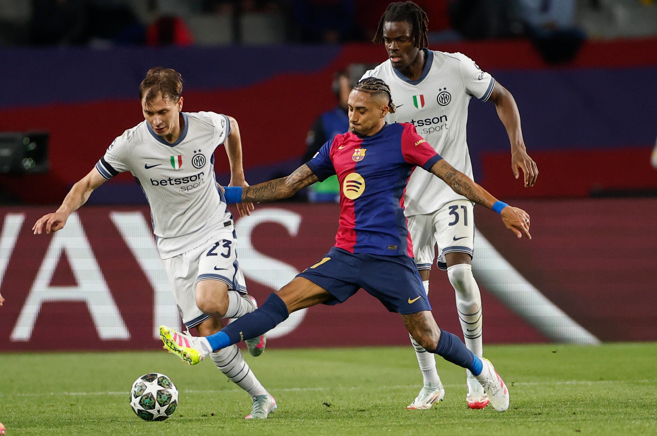 El centrocampista del Inter, Nicolò Barella (i), intenta llevarse el balón ante el delantero brasileño del FC Barcelona, Raphinha, durante el encuentro correspondiente a la ida de las semifinales de la Liga de Campeones en el estadio Olímpico Lluis Company, en Barcelona. EFE / Alberto Estevez.