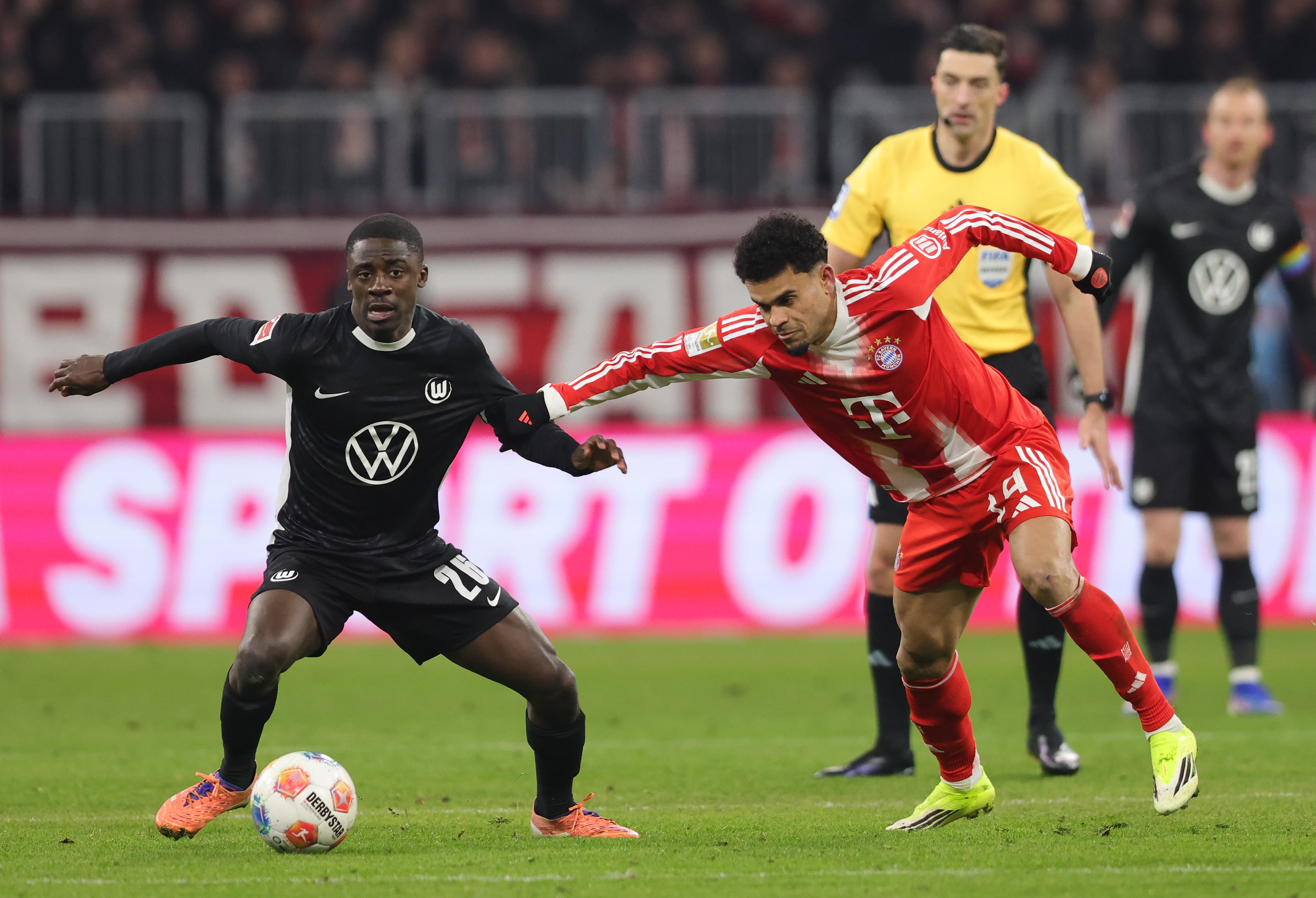 MUNICH, GERMANY - JANUARY 11: Sael Kumbedi of VfL Wolfsburg (L) and Luis Diaz of FC Bayern München compete for the ball   during the Bundesliga match between FC Bayern München and VfL Wolfsburg at Allianz Arena on January 11, 2026 in Munich, Germany. (Photo by Marcel Engelbrecht - firo sportphoto/Getty Images)