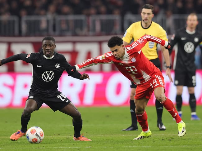 MUNICH, GERMANY - JANUARY 11: Sael Kumbedi of VfL Wolfsburg (L) and Luis Diaz of FC Bayern München compete for the ball during the Bundesliga match between FC Bayern München and VfL Wolfsburg at Allianz Arena on January 11, 2026 in Munich, Germany. (Photo by Marcel Engelbrecht - firo sportphoto/Getty Images)