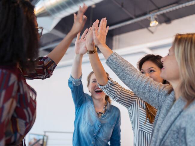 Mujeres unidas juntando la palma de sus manos (Foto vía Getty Images)