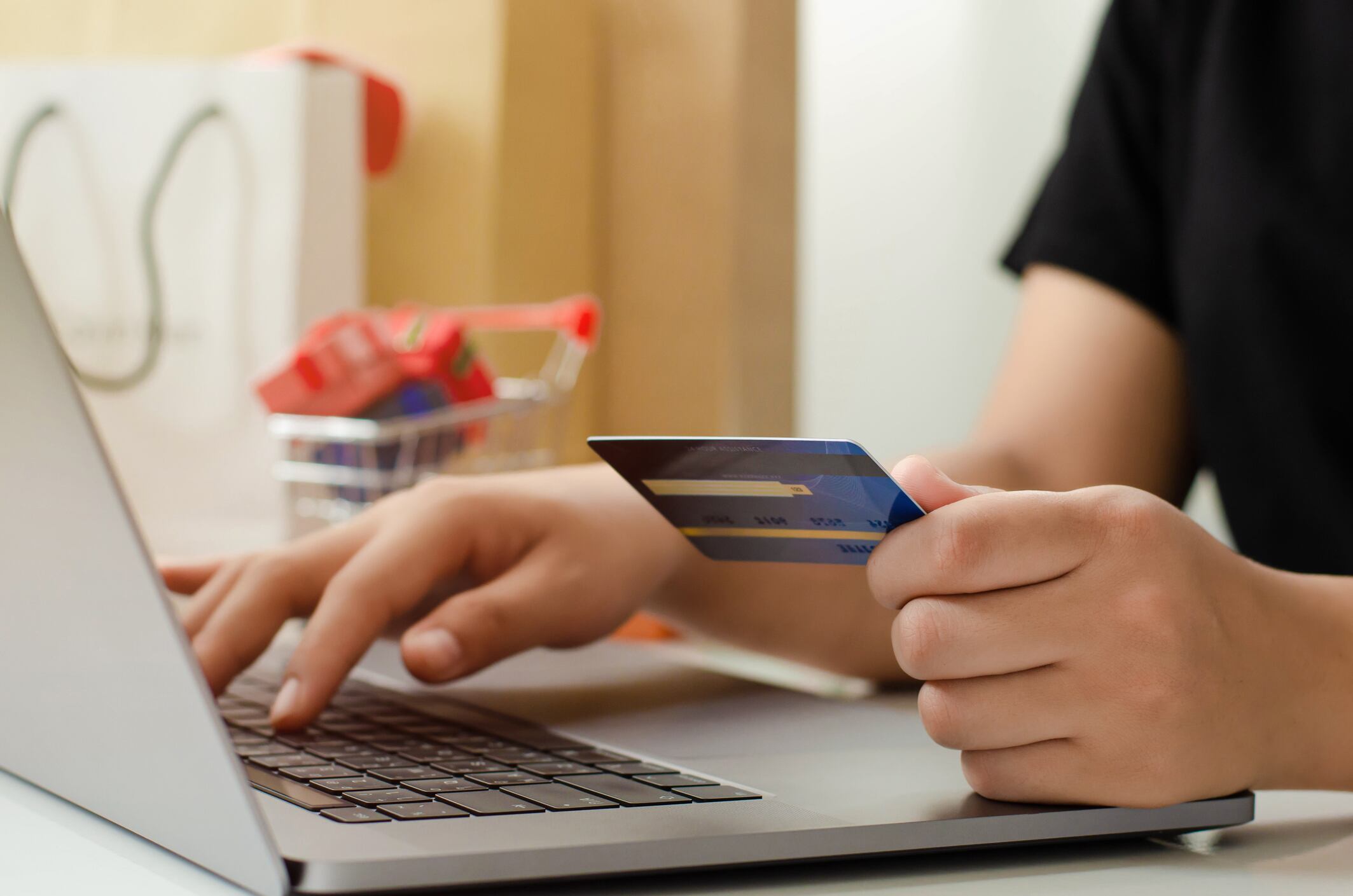 Persona con una tarjeta, escribiendo en una computadora portátil (Foto vía Getty Images)