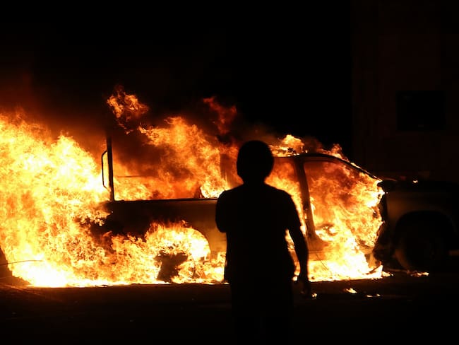 TIXTLA (MÉXICO), 09/03/2024.- Una persona observa una patrulla de la Guardia Nacional (GN) incendiada por supuestos estudiantes normalistas este sábado en municipio de Tixtla, estado de Guerrero (México). Presuntos estudiantes de Ayotzinapa quemaron dos patrullas de la Guardia Nacional en el municipio de Tixtla, en el sureño estado mexicano de Guerrero, y retuvieron a unos 10 agentes, como parte de las protestas que desencadenó el asesinato de su compañero Yanqui Kothan Gómez Peralta, la noche del jueves. EFE/José Luis de la Cruz