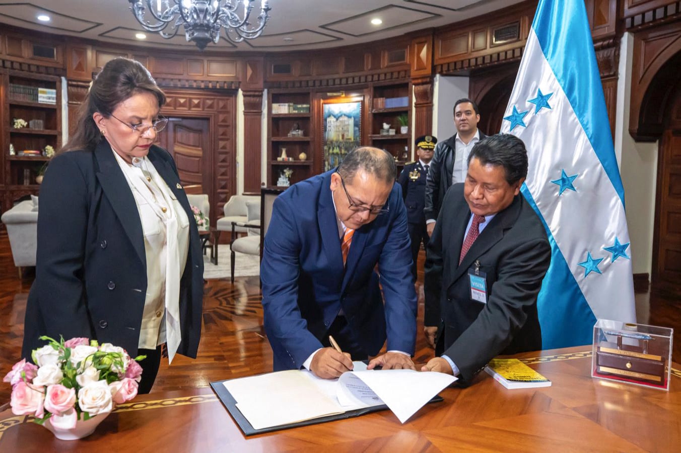 In this handout picture released by Honduran Presidency President Xiomara Castro (L) observes the director of the National Police, General Gustavo Sanchez (C), who signs after being sworn in as the new Minister of Security, in Tegucigalpa on June 21, 2023. A vicious battle with guns and fire left at least 46 women dead in a women's jail in Honduras, a country with a particularly high rate of prison violence and more than 1,000 inmate deaths in 20 years. As the first bodies were handed over to mourning families for burial, the prosecutor's office on Wednesday updated the confirmed toll from 41. (Photo by Handout / Honduran Presidency / AFP) / RESTRICTED TO EDITORIAL USE - MANDATORY CREDIT "AFP PHOTO / HONDURAN PRESIDENCY " - NO MARKETING - NO ADVERTISING CAMPAIGNS - DISTRIBUTED AS A SERVICE TO CLIENTS