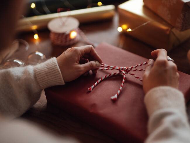 Persona abriendo un regalo en época de navidad (Foto vía Getty Images)