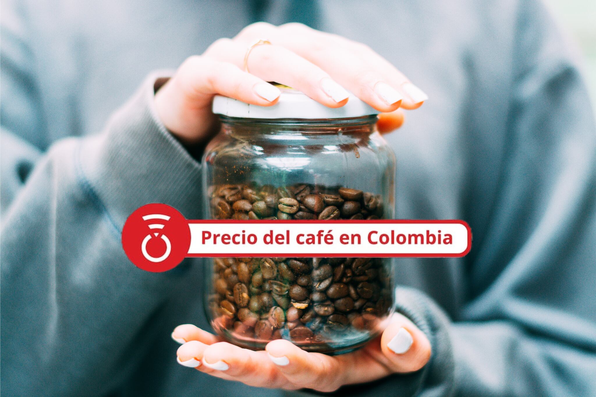 Primer plano de unas manos sosteniendo un frasco de vidrio lleno de granos de café. - Foto Getty Images