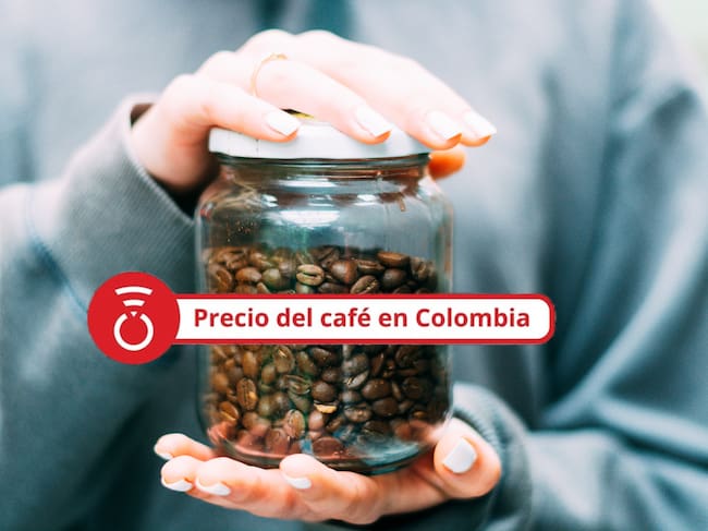 Primer plano de unas manos sosteniendo un frasco de vidrio lleno de granos de café. - Foto Getty Images