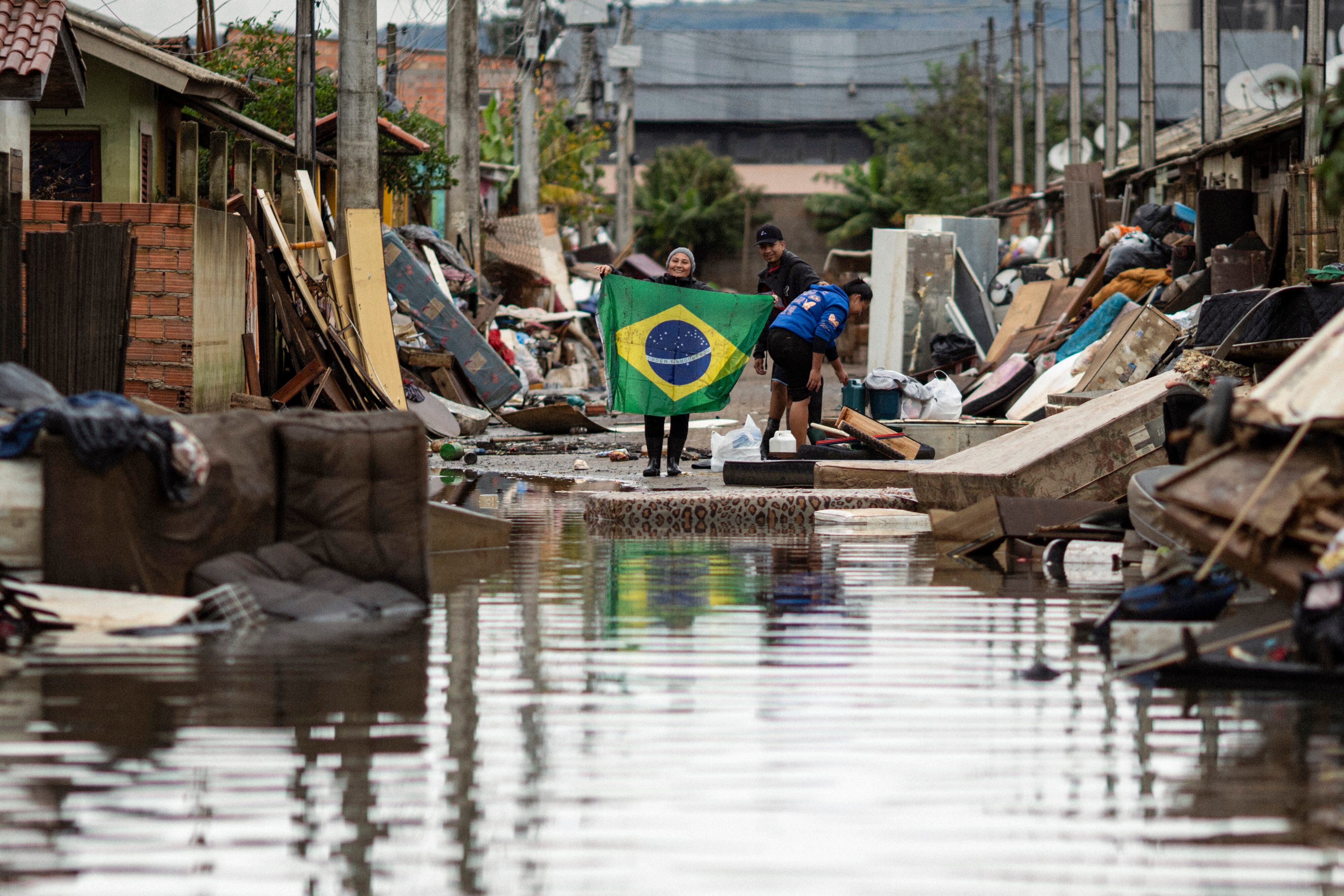 Una mujer sostiene una bandera de Brasil en medio de una calle afectada por las inundaciones, este lunes en Porto Alegre, Rio Grande do Sul (Brasil). EFE/ Daniel Marenco