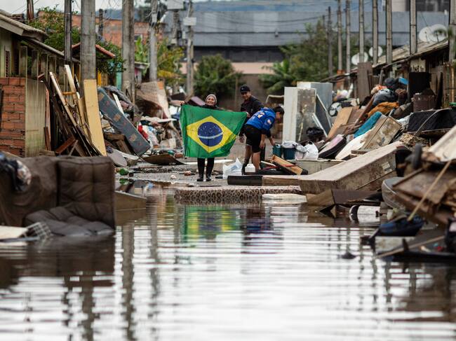 Una mujer sostiene una bandera de Brasil en medio de una calle afectada por las inundaciones, este lunes en Porto Alegre, Rio Grande do Sul (Brasil). EFE/ Daniel Marenco