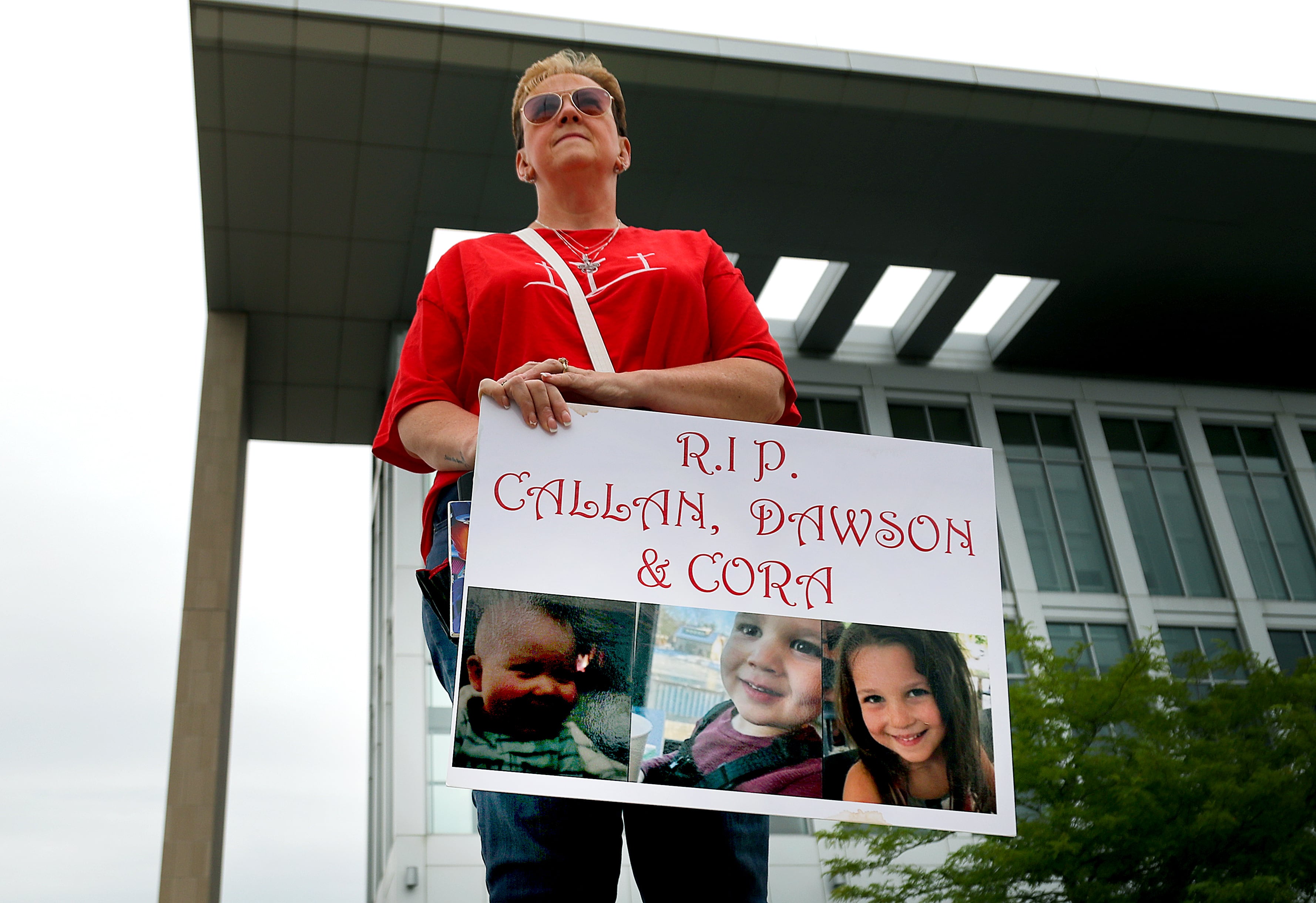 Una mujer sostiene un cartel con la foto de los tres hijos de Clancy a las afueras de la corte. 
(Foto:   John Tlumacki/The Boston Globe via Getty Images)