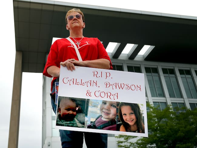Una mujer sostiene un cartel con la foto de los tres hijos de Clancy a las afueras de la corte.
(Foto: John Tlumacki/The Boston Globe via Getty Images)