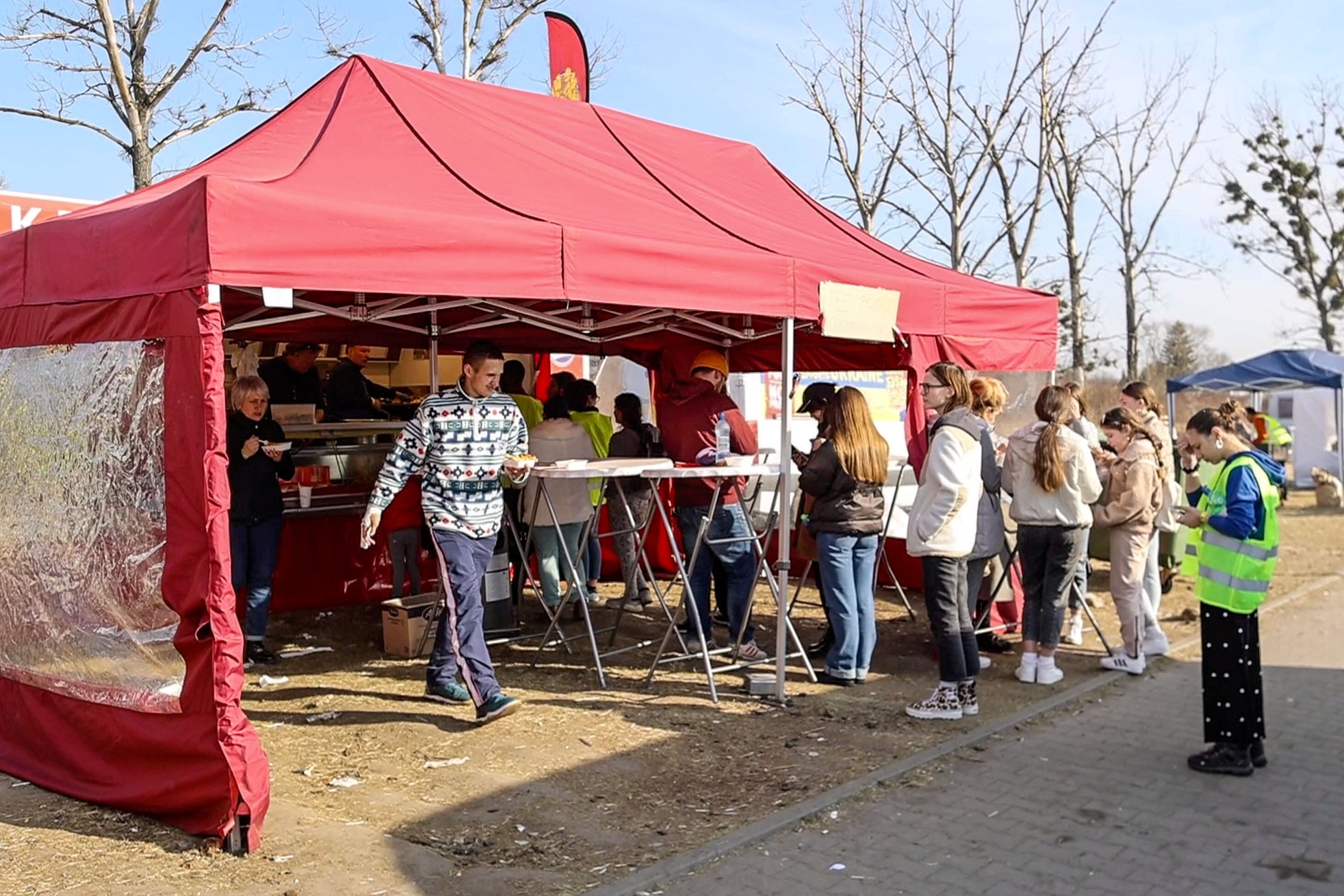 15 March 2022, Poland, Przemysl: Refugees from Ukraine stand at a mobile snack bar with an awning brought here by a group of volunteers from the Dutch. Dutchman van Oosten and his team have been opening a Dutch snack bar at the registration center for refugees in Przemysl for several days. There, refugees get free fries, croquettes, meatballs and rooster sticks. About 500 kilograms of fries are distributed a day. The helpers come from Eindhoven. Photo: Christoph Reichwein/dpa (Photo by Christoph Reichwein/picture alliance via Getty Images)