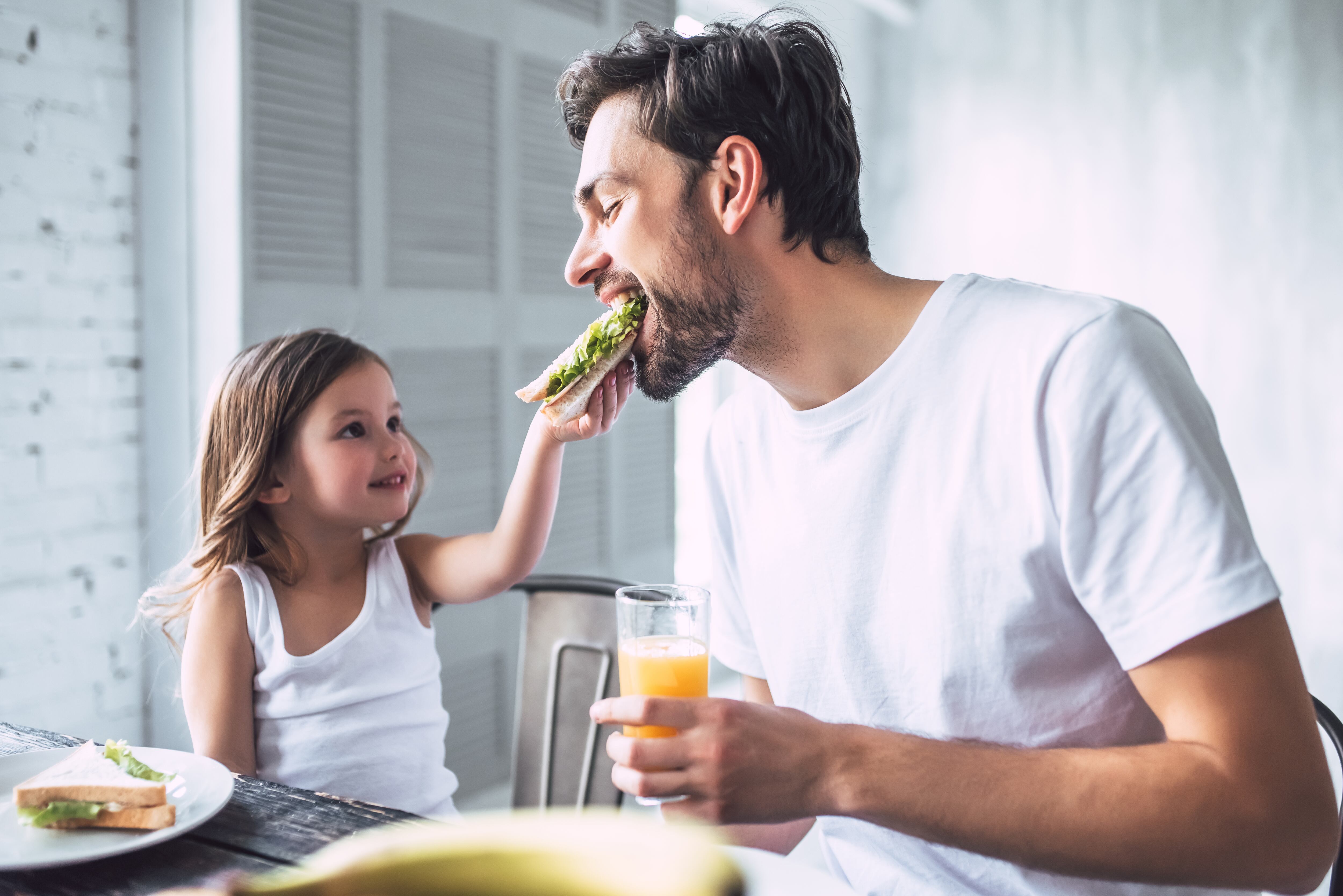 I love you, dad! Handsome young man at home with his little cute girl are having breakfast. Happy Father's Day!
