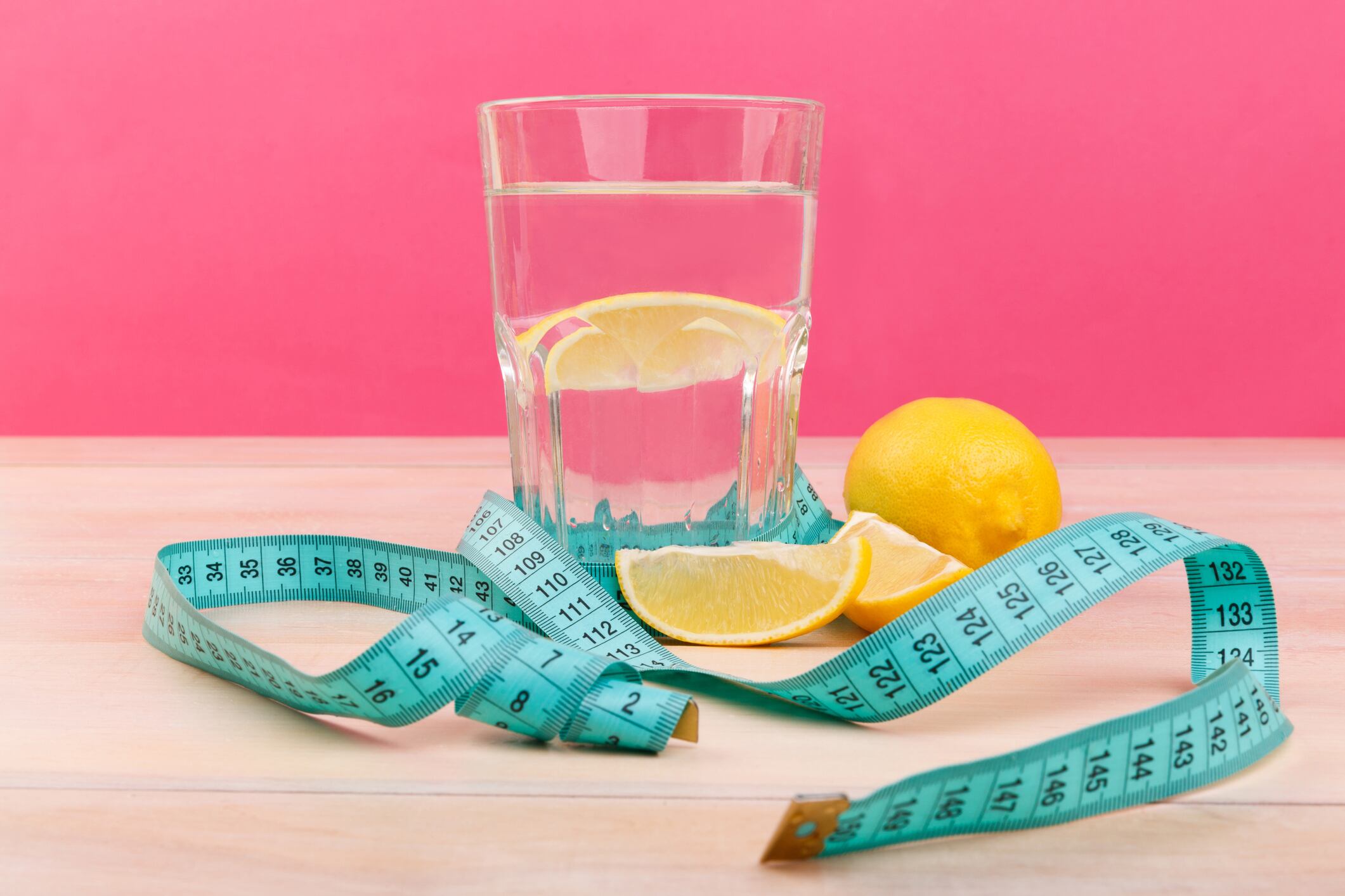 Vaso de agua con limón, junto con una cinta métrica (Getty Images)