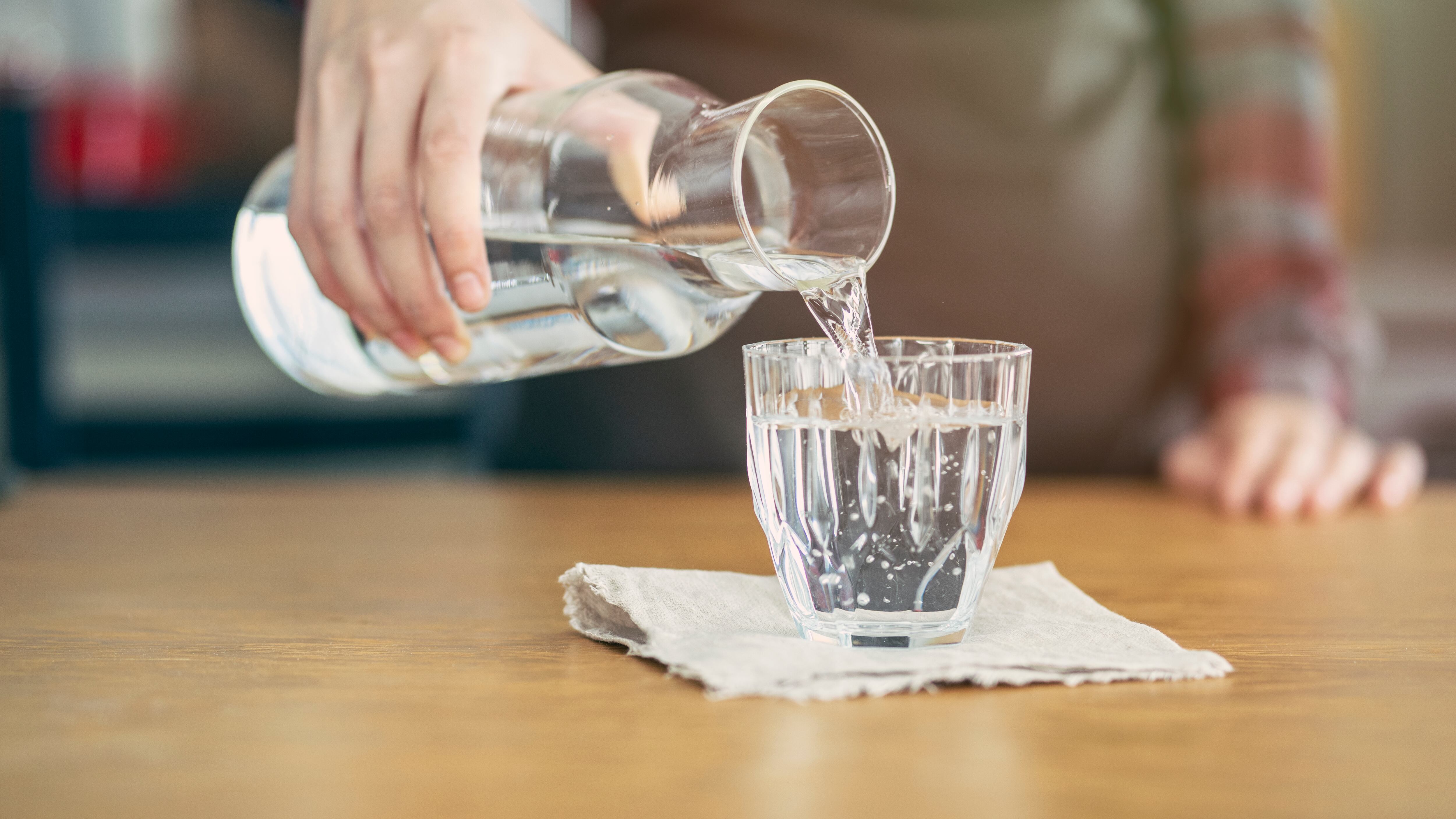 Persona sirviendo agua en un vaso de cristal (Foto vía Getty Images)