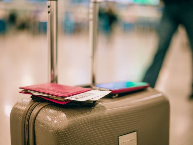 Maleta de viaje con un pasaporte y un teléfono en el aeropuerto (Foto vía Getty Images)