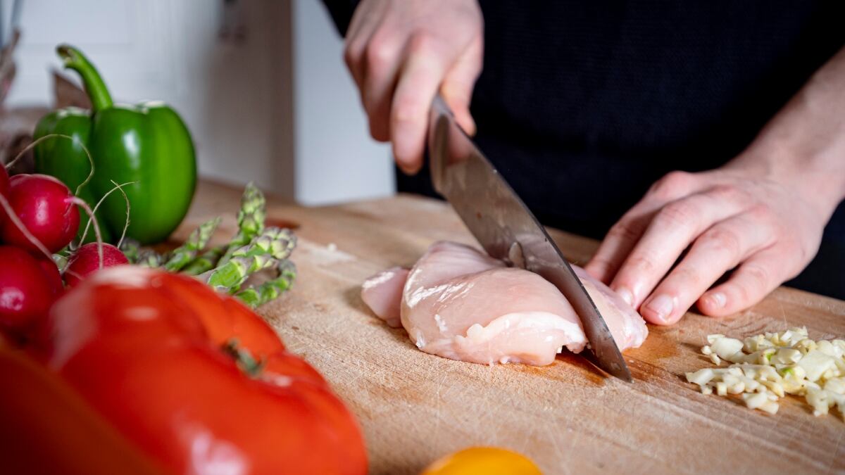Persona preparando una pechuga para cocinarla // Getty Images