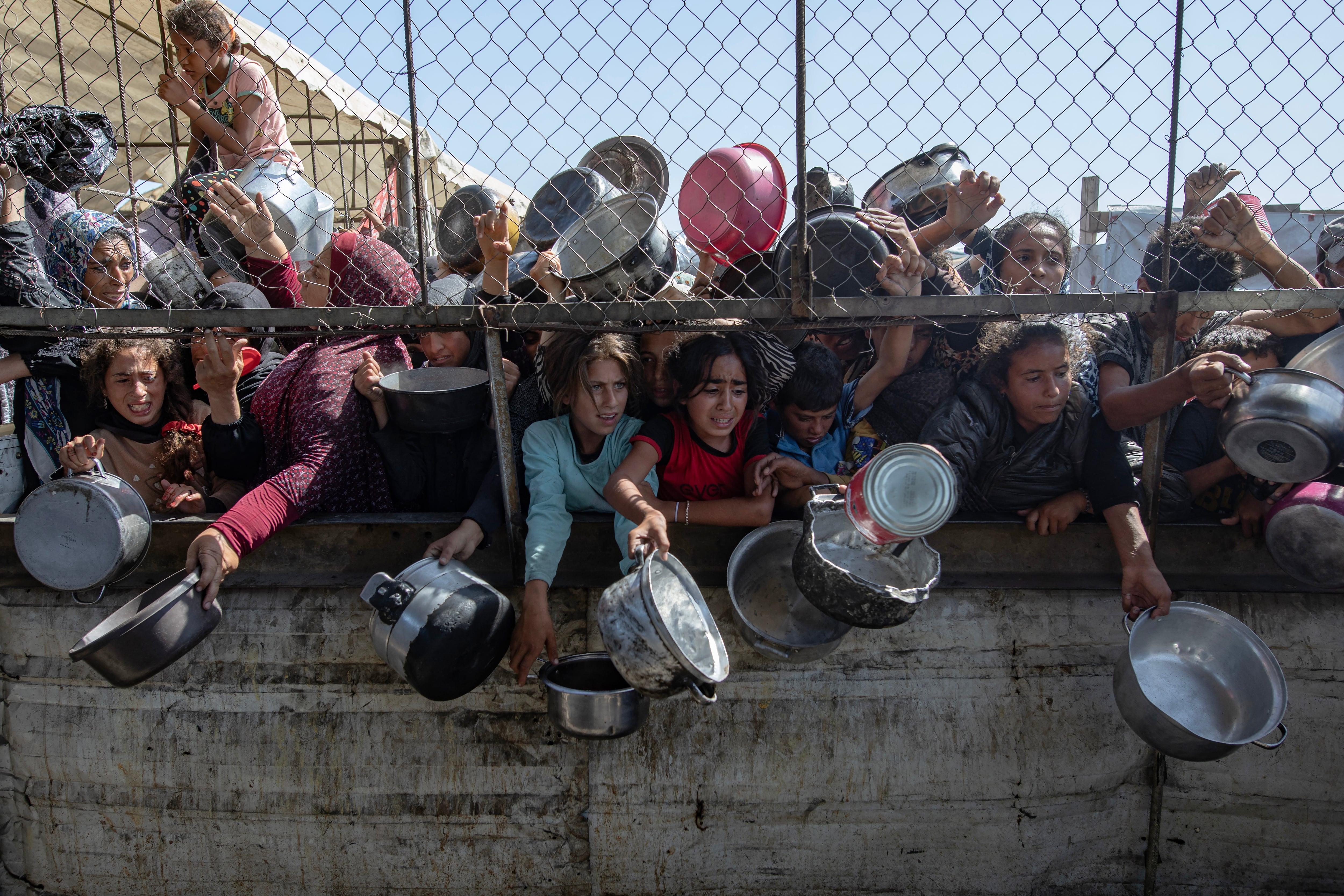 FOTODELDÍA EPA7896. GAZA, 30/05/2025.-GAZA, 30/05/2025.- Palestinos desplazados se agolpan frente a un comedor social para recibir raciones limitadas ante la escasez de alimentos, en Khan Younis, sur de la Franja de Gaza, este viernes. Naciones Unidas advirtió que "toda la población de Gaza corre el riesgo de hambruna" desde que Israel cerró los cruces fronterizos el 2 de marzo de 2025, impidiendo la entrada de suministros esenciales. La Oficina de Medios del Gobierno de Gaza informó el 24 de mayo que al menos 58 personas murieron por desnutrición y casi 250 más por falta de alimentos y medicamentos. EFE/ Haitham Imad