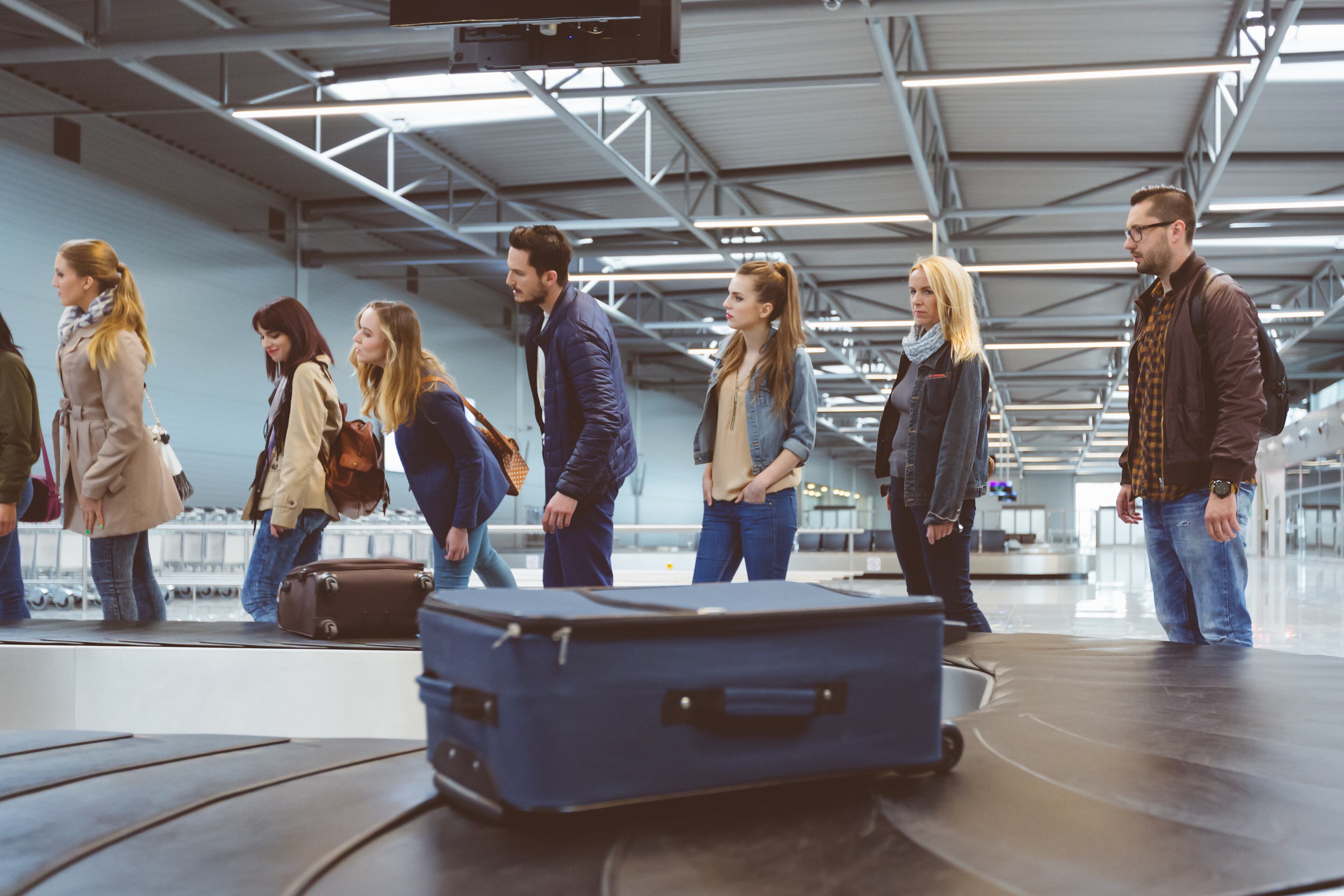 Personas esperando su maleta en una banda de equipaje de un aeropuerto (Foto vía Getty Images)