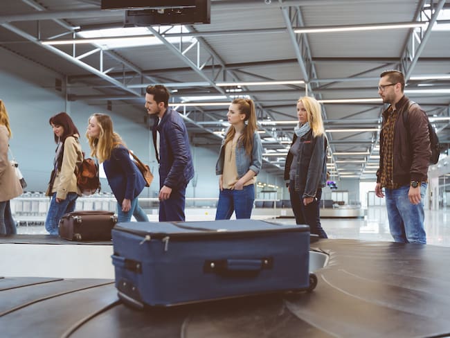Personas esperando su maleta en una banda de equipaje de un aeropuerto (Foto vía Getty Images)