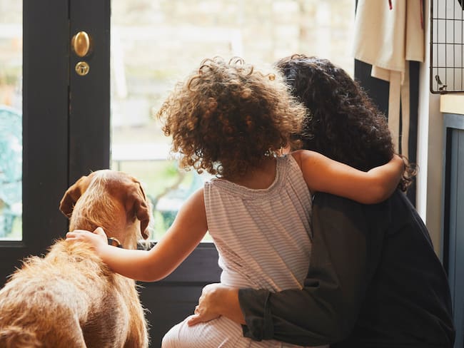 Madre e hija con su perro de espaldas (Getty Images)