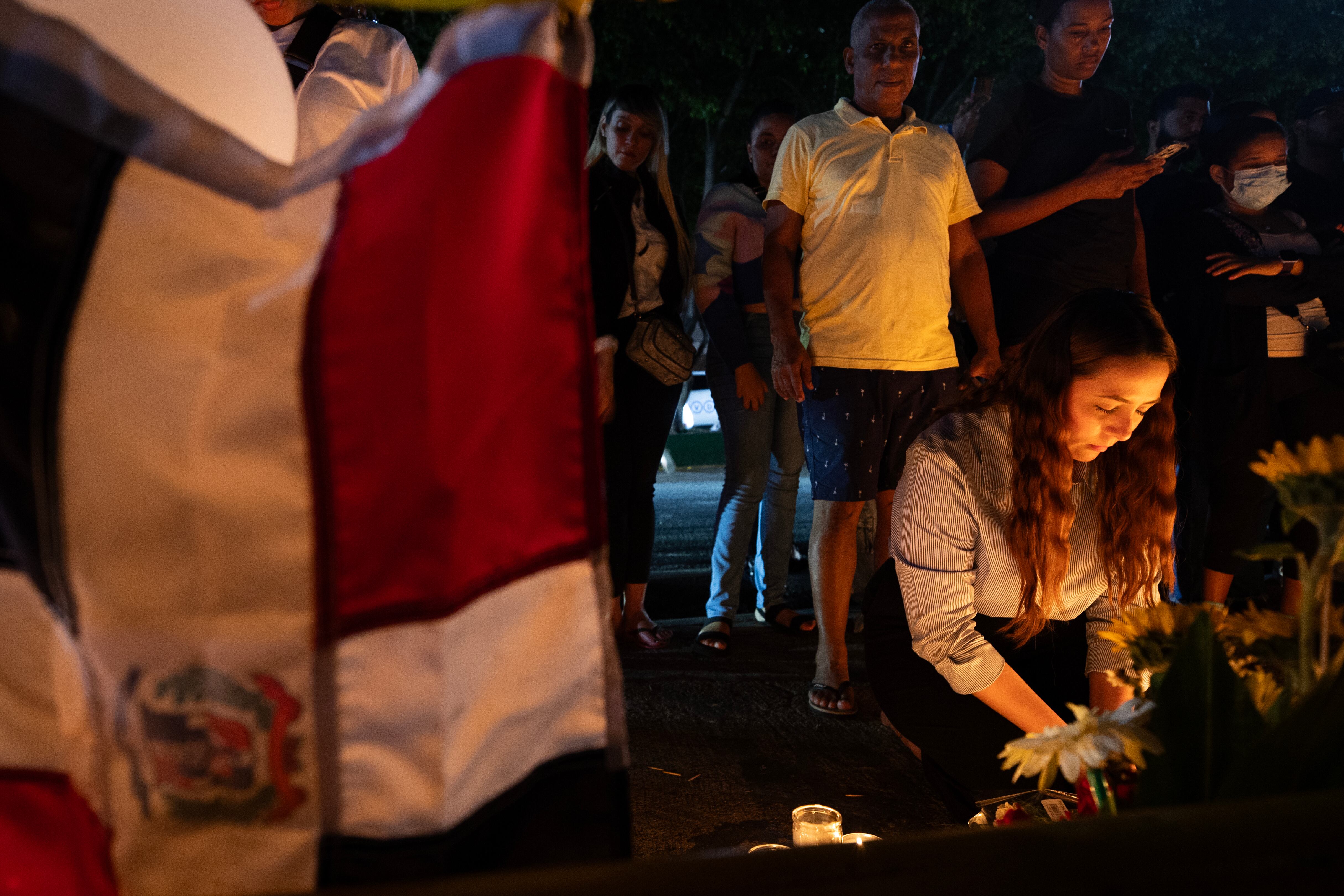 AME8518. SANTO DOMINGO (REPÚBLICA DOMINICANA), 11/04/2025.- Una mujer enciende una vela durante una velatón este viernes en Santo Domingo (República Dominicana). Decenas de personas encendieron velones, portaron globos y depositaron flores en la parte frontal de la discoteca Jet Set, en Santo Domingo, donde la madrugada del martes pasado el derrumbe del techo causó la muerte de 221 personas y heridas a otras 189. EFE/Orlando Barría