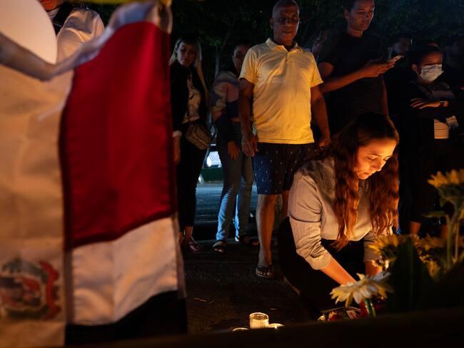AME8518. SANTO DOMINGO (REPÚBLICA DOMINICANA), 11/04/2025.- Una mujer enciende una vela durante una velatón este viernes en Santo Domingo (República Dominicana). Decenas de personas encendieron velones, portaron globos y depositaron flores en la parte frontal de la discoteca Jet Set, en Santo Domingo, donde la madrugada del martes pasado el derrumbe del techo causó la muerte de 221 personas y heridas a otras 189. EFE/Orlando Barría