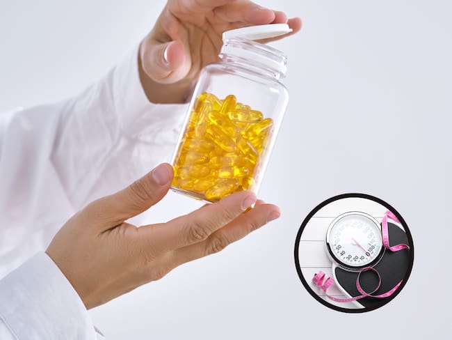 Médico sujetando unas pastillas de omega-3 junto a una bascula (Getty Images)