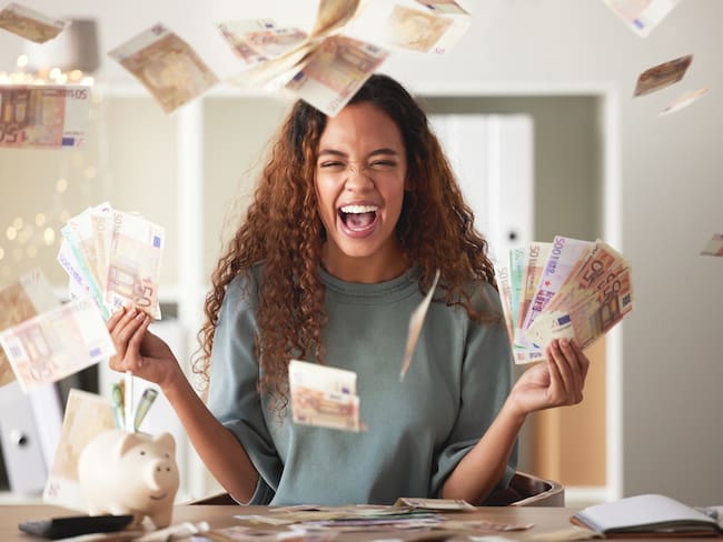 Mujer sintiéndose feliz mientras tiene una gran cantidad de dinero en sus manos / Foto: GettyImages