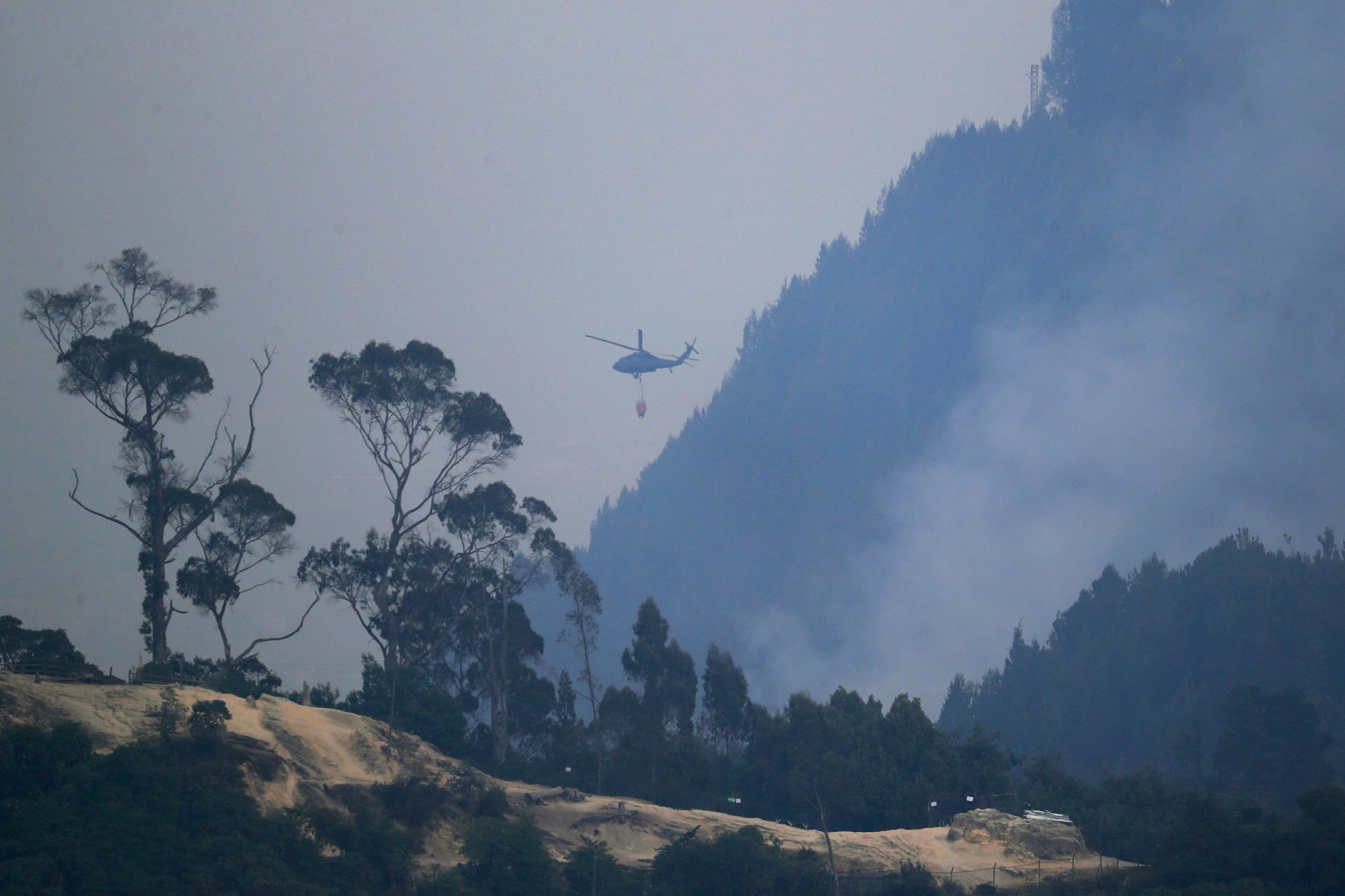 Un helicóptero combate incendio forestal en el cerro El Cable, en Bogotá (Colombia). EFE/ Carlos Ortega