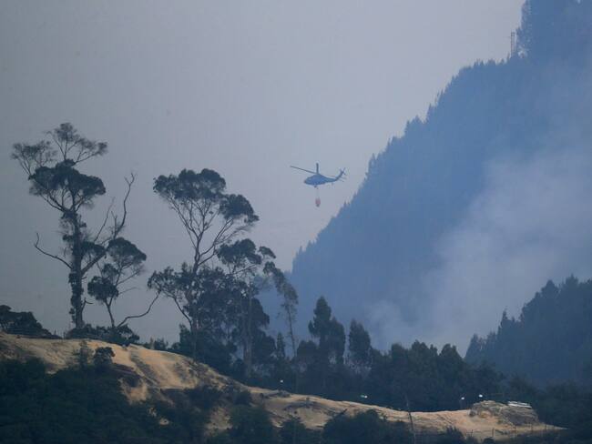 Un helicóptero combate incendio forestal en el cerro El Cable, en Bogotá (Colombia). EFE/ Carlos Ortega