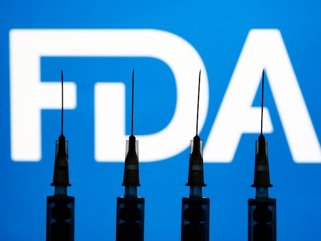 Medical syringes and FDA logo displayed in the background are seen in this illustration photo taken in Krakow, Poland on December 2, 2021. (Photo by Jakub Porzycki/NurPhoto via Getty Images)