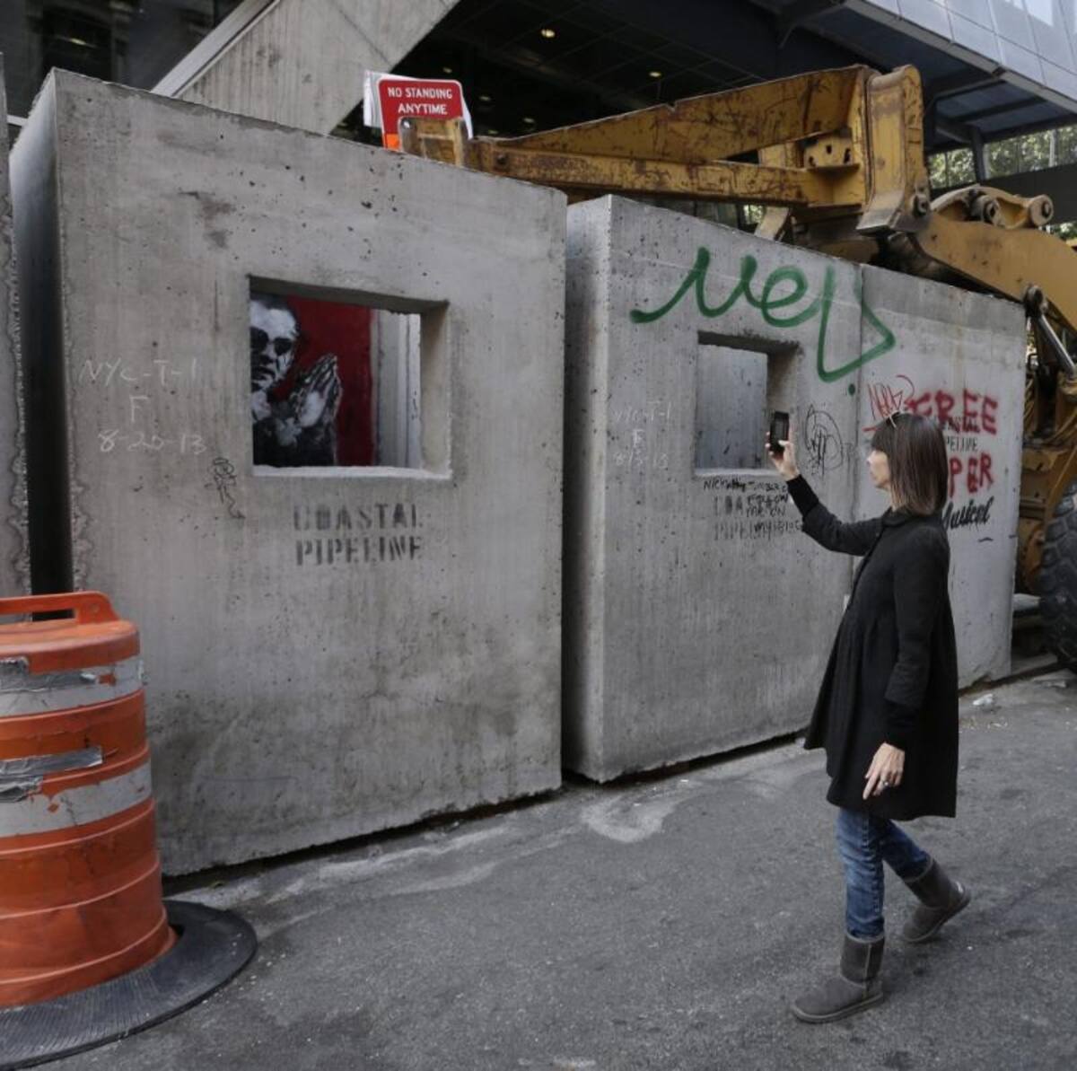 Un viandante hace una foto del graffiti "Confesionario de hormigón (Concrete Confessional)" del artista callejero británico