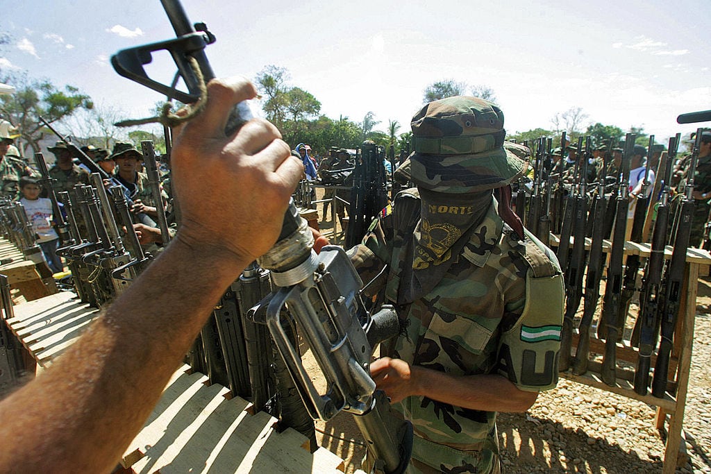 LA MESA, COLOMBIA:  A member of the Colombian United Self -Defense (AUC) right-wing paramilitary guerrillas hands over his weapon during the demobilization ceremony 10 March, 2006 in La Mesa , department of Cesar, Colombia. Paramilitaries fighters demobilized friday in Colombia one the last surrendered arms, according to the schedule agreed with the government of President Alvaro Uribe.  AFP PHOTO/Rodrigo ARANGUA  (Photo credit should read RODRIGO ARANGUA/AFP via Getty Images)