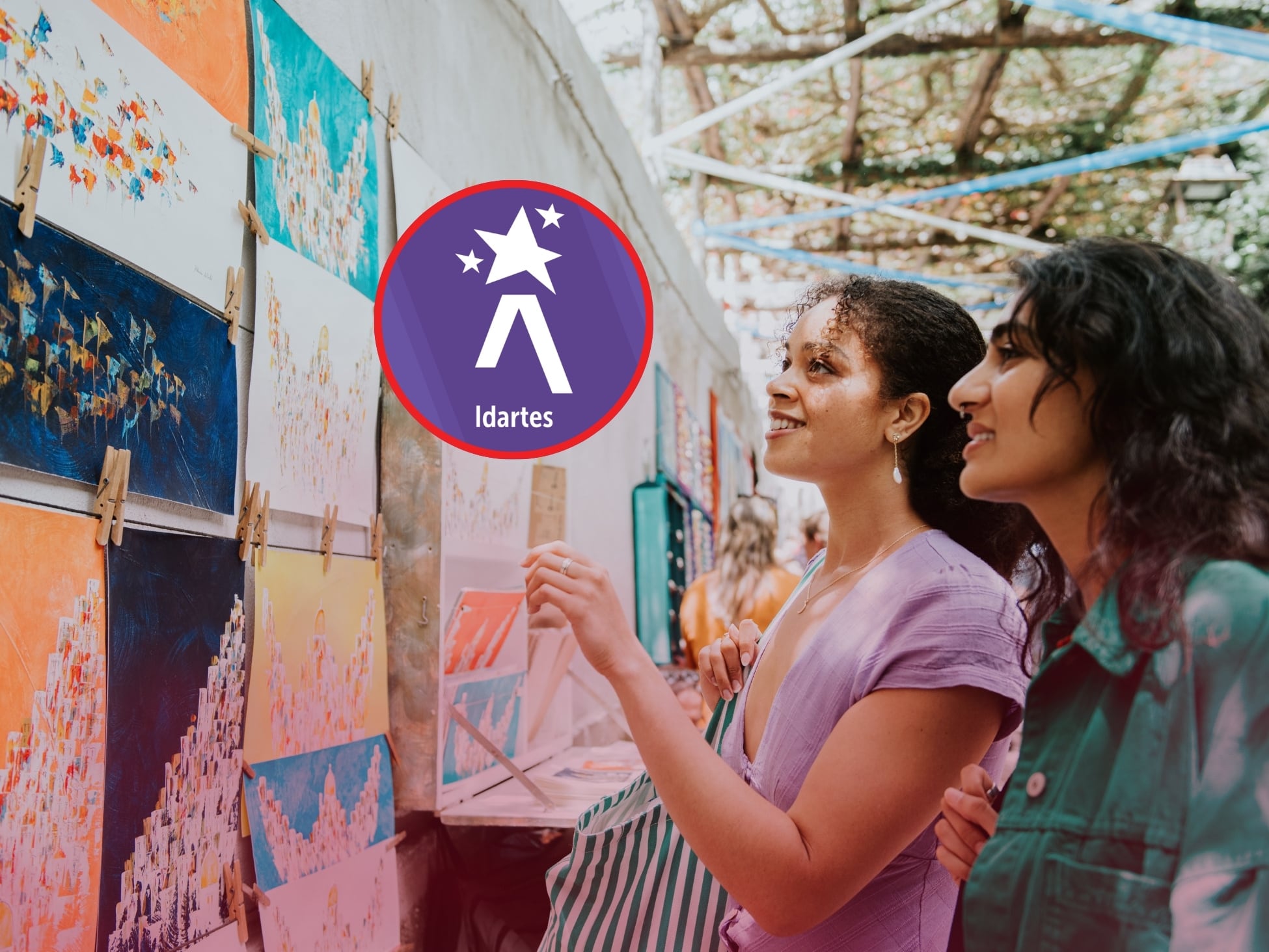 De fondo: Imagen ilustrativa de dos mujeres observando una exposición de arte (Crédito: Getty Images) / Ligeramente arriba a la izquierda: Logo del Instituto Distrital de las Artes de Bogotá (Crédito: Idartes / Alcaldía de Bogotá).
