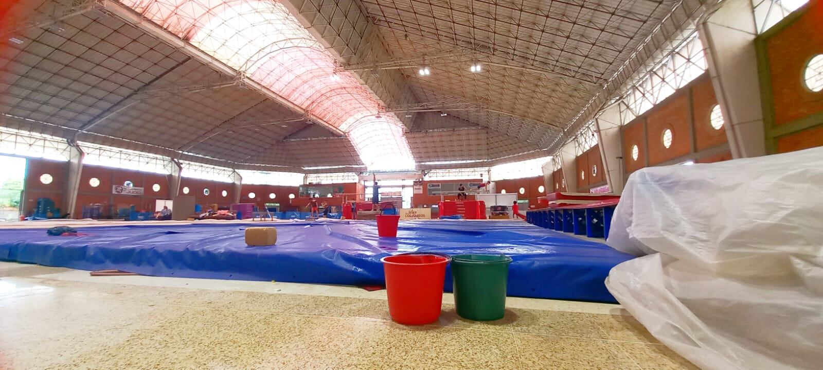Con baldes, deportistas evitan que se moje el escenario