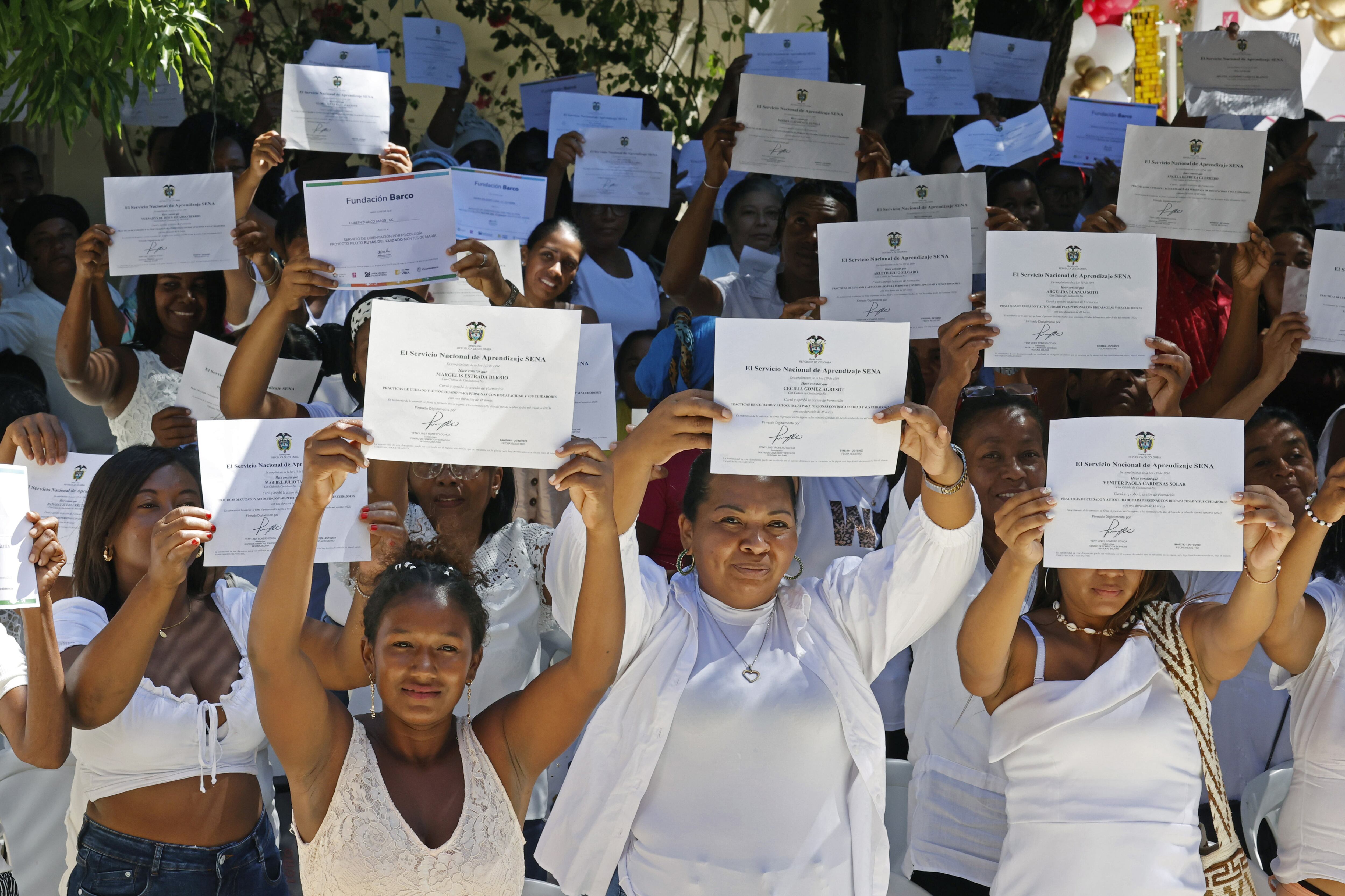 AME3249. SAN JUAN NEPOMUCENO (COLOMBIA), 09/12/2023.- Mujeres cuidadoras alzan los certificados que acaban de recibir luego de cursar el "Taller de apropiación cultural, proyecto piloto Rutas del Cuidado Montes de María" hoy, en San Juan Nepomuceno, departamento de Bolívar (Colombia). Es apenas una cartulina blanca con el logo del Gobierno colombiano, pero que le certifica en cuidados, en reconocimiento de una labor imprescindible en cualquier país pero también invisibilizada, especialmente en zonas rurales como esta. EFE/Mauricio Dueñas Castañeda
